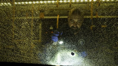 An Israeli security forces member examines a shattered window. Reuters