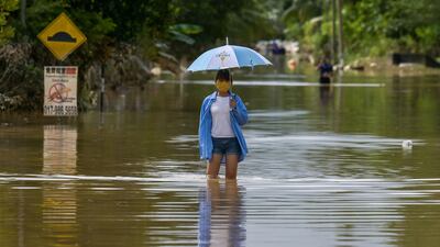 A woman walks along a road submerged by floodwaters following heavy monsoon rains in Mentakab town in Malaysia's Pahang state. AFP