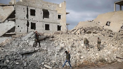 Syrian rebel-fighters walk through the rubble of a building destroyed by a reported air strike from the day before in the rebel-held al-Rashidin district of western Aleppo's countryside. AFP
