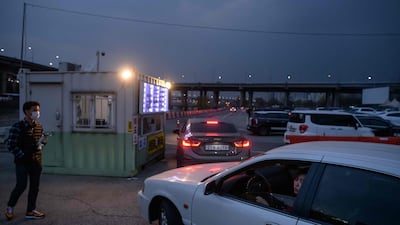 In a photo taken on March 21, 2020 customers queue in their cars to buy tickets at a drive-through cinema in Seoul. AFP