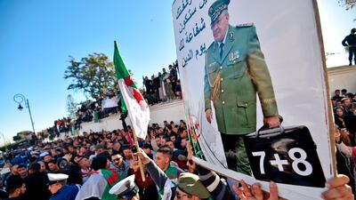 People hold up a portrait of Algeria's late military chief Lt Gen Ahmed Gaid Salah during his funeral in Algiers. AFP