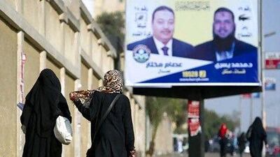 Egyptian veiled women walk past an election campaign billboard for the Islamist, Freedom and Justice Party (FJP) as voters go to polling stations for the run-off of the first round of voting in the Cairo neighbourhood of Nasser City in December. AFP PHOTO/ODD ANDERSEN