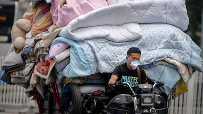 A man rides through Beijing with a load of bedding and other material. AP Photo