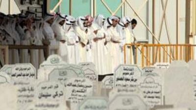 Kuwaiti men pray over the remains of some of the 41 women and children who died in the fire before burying them at Sulaybikhat Cemetery.