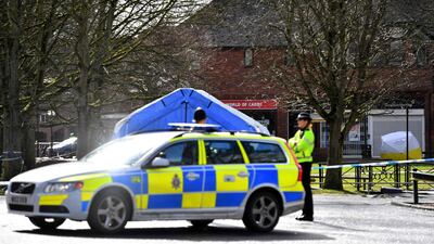 Police stand guard near a bench in Salisbury where Sergei Skripal and, his daughter Yulia, were found after being poisoned with a nerve agent.