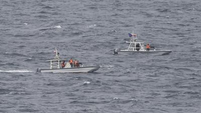 Members of Iran's Revolutionary Guard watch the USS George HW Bush as it travels through the Strait of Hormuz last month. The arrival of the nuclear-powered aircraft carrier to the Gulf marks the first such deployment under new US president, Donald Trump. Jon Gambrell / AP Photo