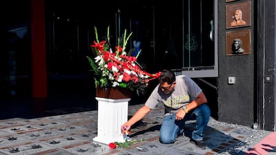Van Halen fan George Salon leaves momentoes, which include flowers, a rose, guitar picks and a cigarette, on the handprints at the Guitar Center in Hollywood, California of late rock guitarist Eddie Van Halen on October 6, 2020. AFP