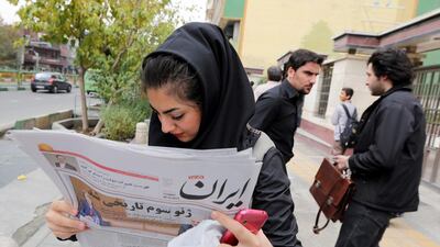 An Iranian girl reads a copy of the Iran newspaper with a headline translating 'Third Geneva was historical' outside a kiosk in Tehran. Abedin Taherkenareh / EPA
