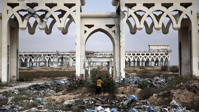 This picture taken on August 18, 2014 shows a Palestinian boy picking flowers in front of the destroyed and deserted main gate of Gaza Strip’s former international airport in the southern town of Rafah. As the ceasefire takes hold, Gazans are starting to dream again of the possibility of the airport's reopening. Thomas Coex/AFP Photo