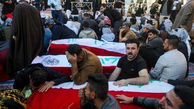 Iraqis mourn next to the coffins of victims of a militant attack, in a village west of Baghdad on Tuesday. AP