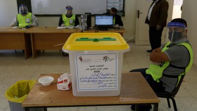 A ballot box is seen as electoral workers sit in a polling station during parliamentary elections in Amman. Reuters