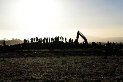 People watch as a tractor excavates the scene of the Ethiopian Airlines Flight ET 302 plane crash. Reuters