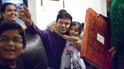 Eva Suares, 3, hugs her father Ryan Suares before receiving her Christmas present at Preci D’Souza’s home in Bur Dubai. Razan Alzayani / The National