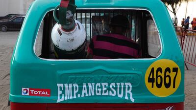 A man leaves in a moto-taxi with his full oxygen tank, after waiting for three days for a refill in the poor area of Villa El Salvador, in Lima, Peru. AP Photo