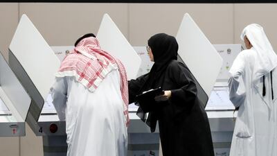 An election official helps a voter to use the electronic voting system