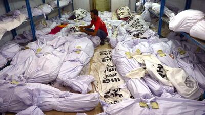 A volunteer puts an identification paper onto a body of a heatwave victim as other dead bodies are seen in the the cold storage of the Edhi morgue in Karachi, Pakistan. Rizwan Tabassum / AFP