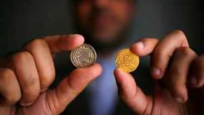 Farhat Hussain holds a silver dirham coin, left, from 770AD found in Scandinavia and a gold dinar coin from 920AD found in Russia. Both were produced in Baghdad.