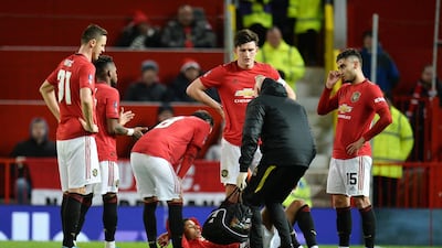 Manchester United players stand around their teammate Marcus Rashford. EPA