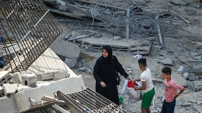 A Palestinian mother and her children inspect the rubble of their apartment at the destroyed Al Aklouk Tower following Israeli air strikes on Gaza City on Sunday. EPA