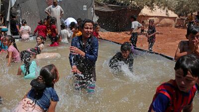 Syrian children play in a portable swimming pool set up by volunteers, at a camp for the displaced in the rebel-held town of Kafr Yahmul in Idlib.