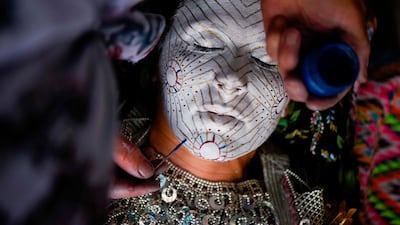 As part of the centuries old tradition, old ladies prepare young brides, painting their faces in many layers of colors while the golden circles symbolize the cycles of life. AFP