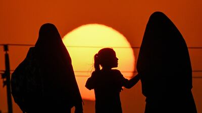 Two women and a girl march with other Shiite Muslim devotees in the Midaina district of Iraq's Basra province at sunset. AFP