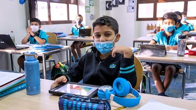 The children wear face masks and the tables are spaced out.
