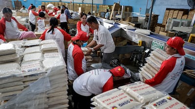 Volunteers and local government assistance beneficiaries pack food boxes in Manila. EPA