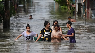 People wade through a waist-deep flood in Barangay Marulas. Reuters
