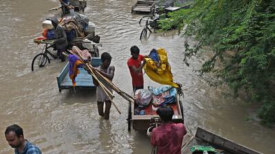 People with their belongings wade through floodwaters from the Yamuna river. AFP