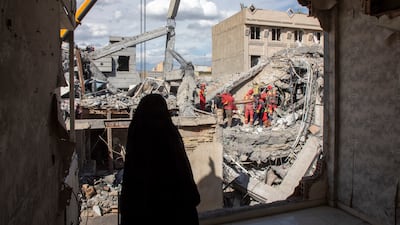 A woman looks on as residents and emergency workers sift through rubble of a residential building that was hit in an air strike in Tehran in late March. Getty Images