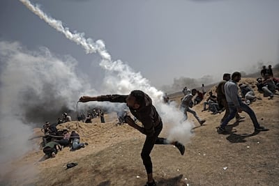 A Palestinian protester throws back an Israeli tear-gas canister during near the border with Israel in the northern Gaza Strip. Mohammed Saber / EPA