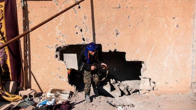 A fighter with the Syrian Democratic Forces walks through a hole in the wall in the frontline Syrian village of Baghouz. AFP