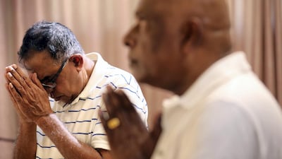 Men hold their hands in prayer before the statue of Buddha in Dubai's only Buddhist temple. Chris Whiteoak / The National
