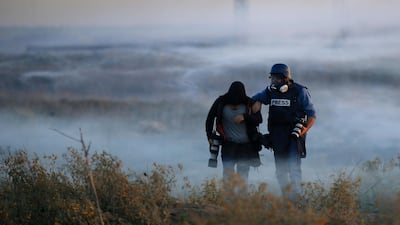 Palestinian press photographers walk amid tear gas smoke during clashes with Israeli forces on December 11, 2017 near the border fence with Israel, east of Gaza City. Mohammed Abed / AFP