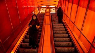 A pedestrian wears a protective face mask while travelling down a walkway escalator in Tehran, March 15. Bloomberg