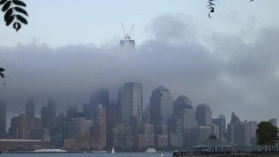 People walk on a pier by the Hudson River as clouds shroud One World Trade Center and the skyline of Lower Manhattan in New York. Gary Hershorn / Reuters
