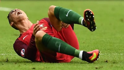 Cristiano Ronaldo hold his thigh as he rolls on the ground after being hurt during Portugal's Euro 2016 final with France in Paris on July 10, 2016. Franck Fife / AFP