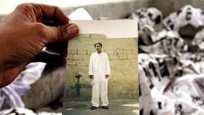 A man carries a picture of a relative as he tries to identify his body at a mortuary in Karachi.