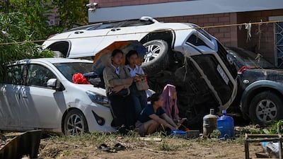 People sit beside a piles of cars in the aftermath of Typhoon Kalmaegi in Liloan. AFP
