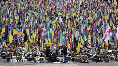 People mourn at the graves of Ukrainian servicemen in Lychakiv cemetery on the Day of the Armed Forces of Ukraine, in Lviv. AFP