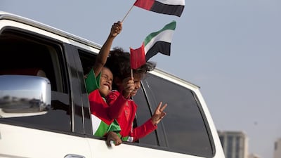 Children raise their flags to join celebrations of the 41st UAE National Day during the Union Car Parade on Yas Island, Abu Dhabi. Silvia Razgova / The National