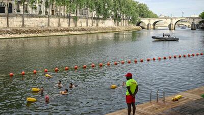 A lifeguard stands on duty as people swim at the Pont Marie on the River Seine, Paris. AFP