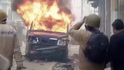 Police personnel look at a burning vehicle during clashes over citizenship law in Bulandshahar, Uttar Pradesh. Reuters