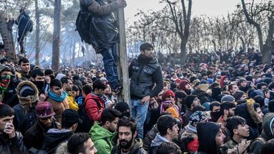 TOPSHOT - Migrants gather inside the buffer zone of the Turkey-Greece border, at Pazarkule, in Edirne district, on February 29, 2020. Thousands of migrants stuck on the Turkey-Greece border clashed with Greek police on February 29, 2020, according to an AFP photographer at the scene. Greek police fired tear gas at migrants who have amassed at a border crossing in the western Turkish province of Edirne, some of whom responded by hurling stones at the officers. The clashes come as Greece bolsters its border after Ankara said it would no longer prevent refugees from crossing into Europe following the death of 33 Turkish troops in northern Syria. / AFP / BULENT KILIC
