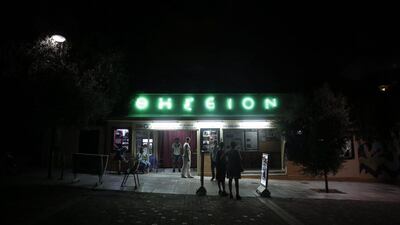 Passers-by looks at movie notices outside the Thisio outdoor summer cinema where moviegoers watch films under the ancient Acropolis.