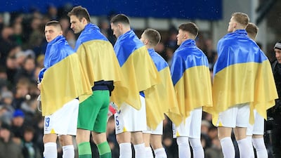Vitaliy Mykolenko (L) and teammates stand draped in national flags of Ukraine. AFP
