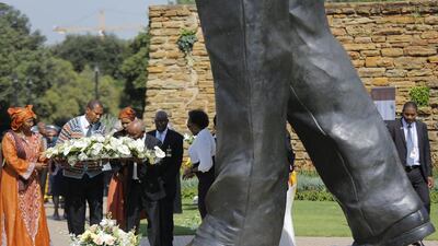 Nelson Mandela’s grandson, Mandla Mandela, second left, lays flowers at the feet of a huge statue during a memorial in Pretoria. Kim Ludrook / EPA