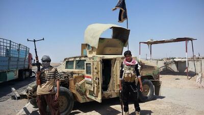 Islamic State group militants stand with a captured Iraqi Army Humvee at a checkpoint outside Beiji refinery. In all, ISIL is thought to control up to 11 oil refineries across Syria and Iraq (AP Photo)