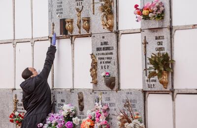 A woman wearing a face mask and gloves touches a niche during the burial of a man who died of the new coronavirus in Madrid. AFP